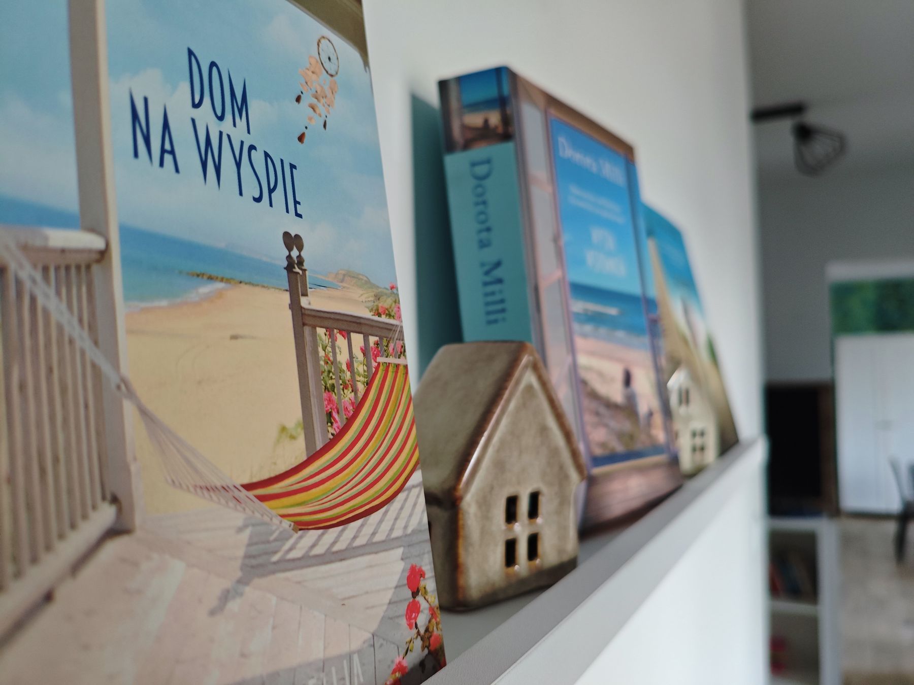 Ceramiczny domek obok książek na półce